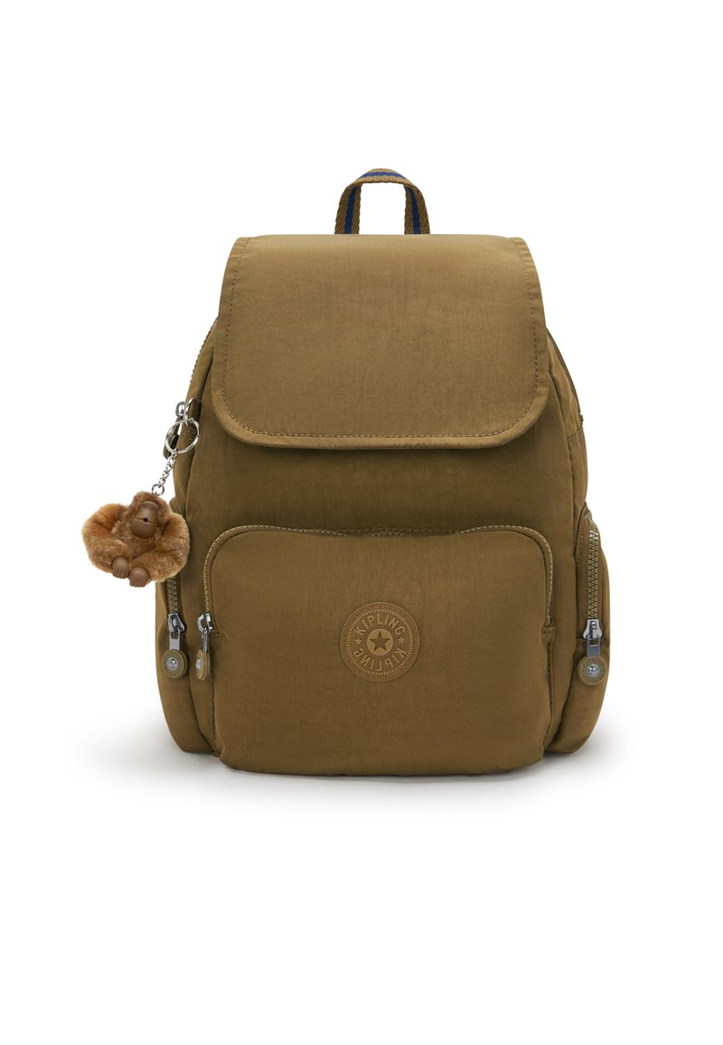 Mochila de tela marrón con cierre de solapa, bolsillos con cremallera y un llavero con un charm de mono. Presenta un logo en la parte frontal y una superficie texturizada.