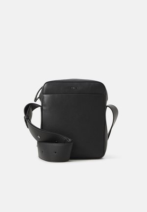 Sac à bandoulière rectangulaire en cuir noir avec une large sangle réglable et un petit logo à l'avant sur fond blanc.