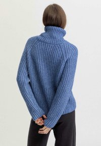 Blauer Strickpullover mit Rollkragen, gerippter Struktur und langen Ärmeln. Hat eine lockere Passform und sichtbare Nähte auf der Rückseite.