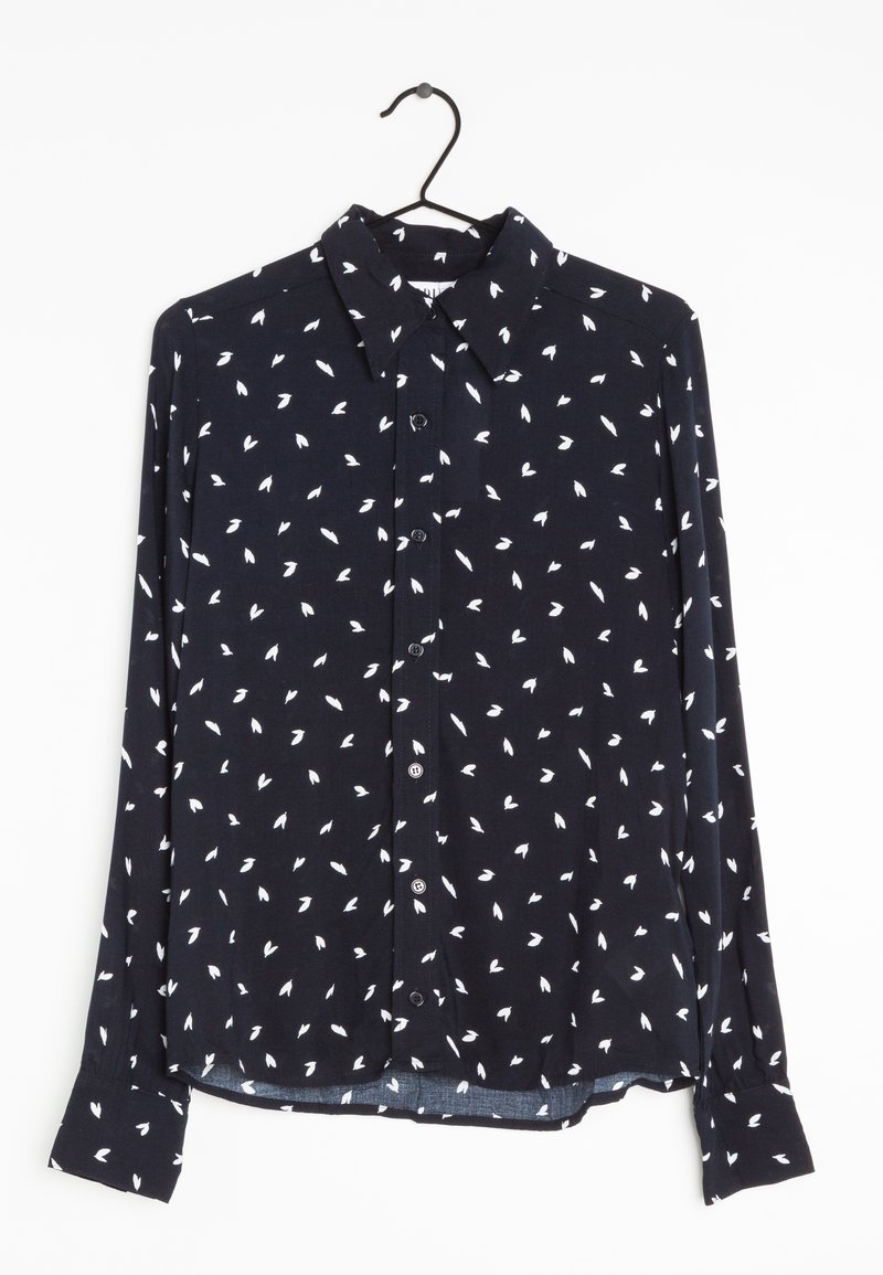 Chemise noire à manches longues à boutons avec motif abstrait de feuilles blanches suspendue sur un cintre noir, fond blanc.