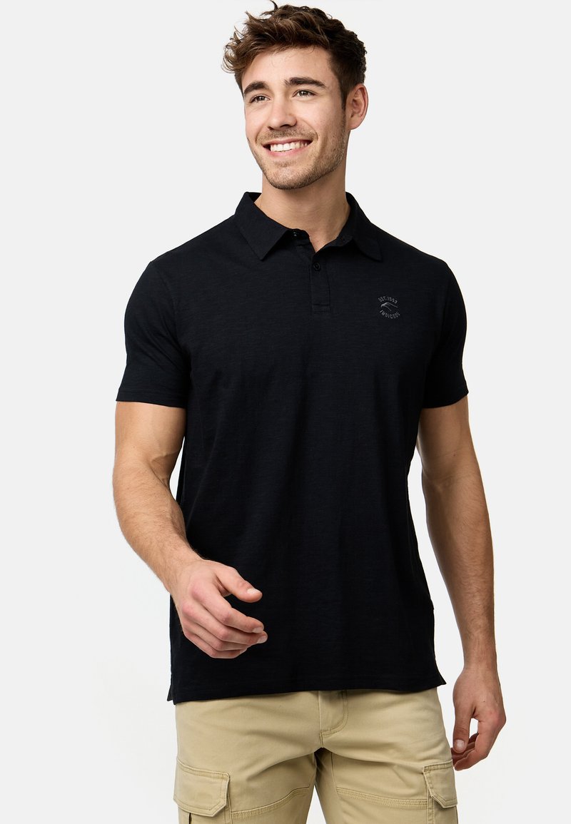 Sort polo skjorte med krave, korte ærmer og et lille logo på brystet. Lavet af blødt stof, med en afslappet pasform og sideslidser.