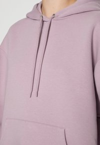 Lila sweatshirt med huva, dragsnören, en framficka och ett mjukt, texturerat material. Enkelt och avslappnat design.