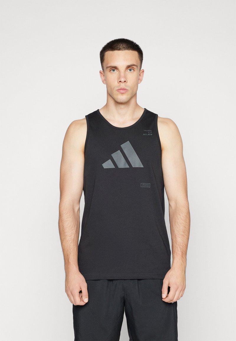 Canottiera nera sportiva realizzata in tessuto traspirante, con logo Adidas grigio e un piccolo dettaglio testuale sulla parte superiore sinistra. Girocollo.
