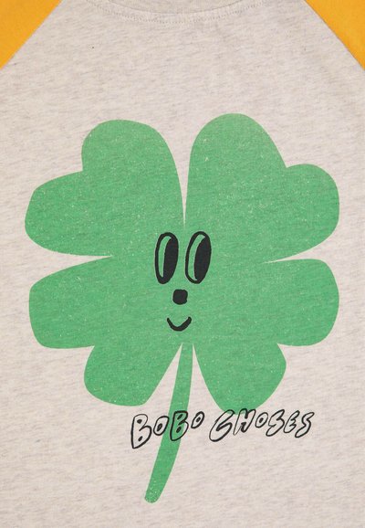Light gray t-shirt with yellow sleeves, featuring a large green four-leaf clover graphic and black text “Bobo Choses” beneath it.