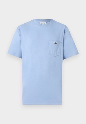 Φωτεινό γαλάζιο T-shirt με κοντά μανίκια και εμπρόσθια τσέπη που φέρει το μικρό πράσινο λογότυπο του κροκόδειλου Lacoste.