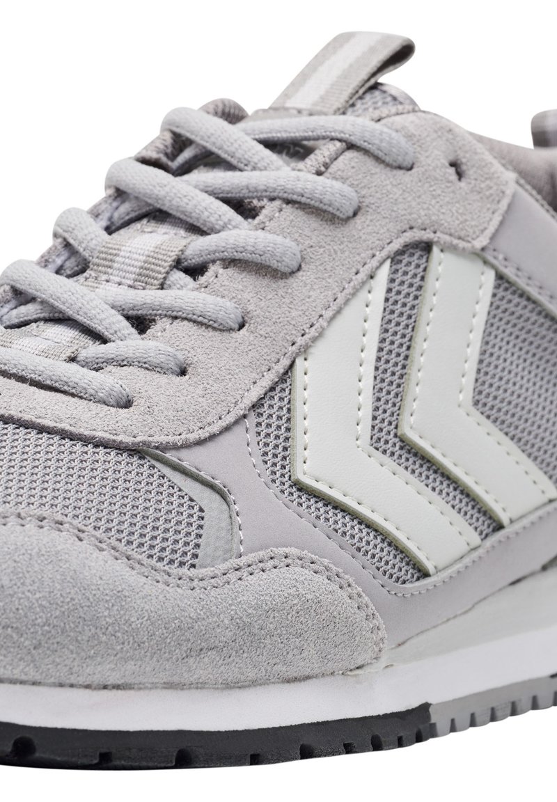 Grijze sneaker met een mix van nubuck en mesh bovenwerk, witte accentstrepen, ronde veters en een gestructureerde rubberen zool.