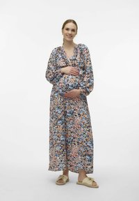 Gravidklänning med blommönster i pastellfärger, långa ärmar och V-ringning. Tillsammans med ljusa, platta sandaler.