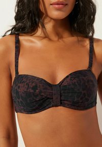 Bikinový top se vzorem leopardí kůže s ozdobným předním uzlem, nastavitelnými ramínky a tmavou barevnou kombinací hnědé a černé. Měkká textura látky.