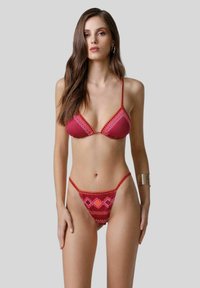 Set di bikini caratterizzato da un profondo colore rosso scuro con motivi geometrici in rosa e arancione, spalline regolabili e copertura minimale per un look moderno.