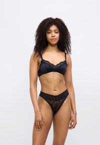 Black lingerie set featuring a lace-trimmed bralette with soft cups and adjustable straps, paired with a matching sheer lace thong.