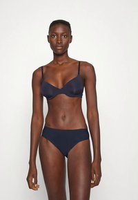 Granatowy stanik i bikini wykonane z gładkiego materiału. Stanik ma cienkie, regulowane ramiączka i subtelne wyściełanie; bikini charakteryzuje się klasycznym krojem i bezszwowym wykończeniem.