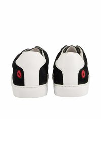 Baskets en suède noir avec des accents blancs, présentant un graphique unique de lèvres rouges sur le talon. Semelle en caoutchouc avec une texture antidérapante.