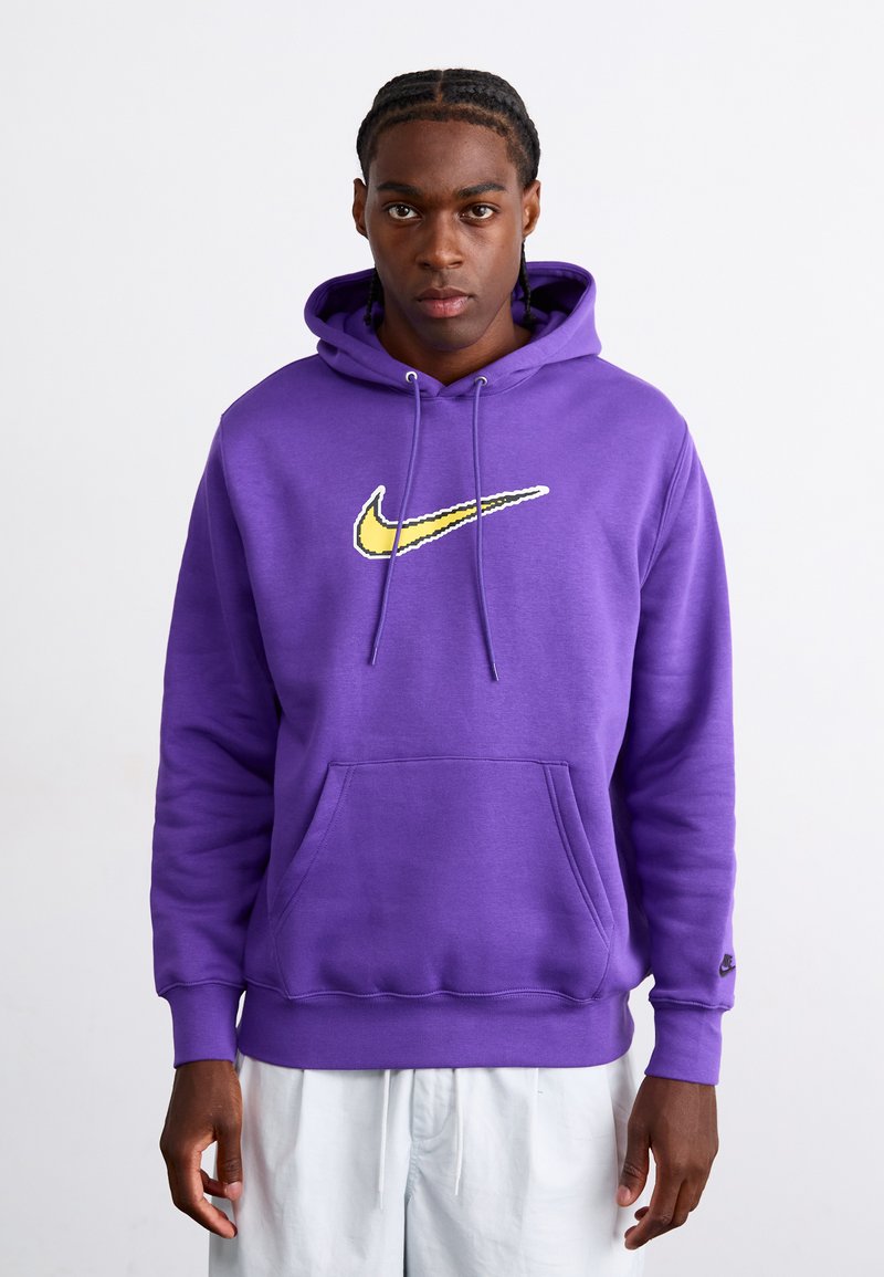 Ljubičasta dukserica od mekanog pamuka, s žutim Nike logotipom na prsima, prednjim džepom i ušicama na kapuljači.