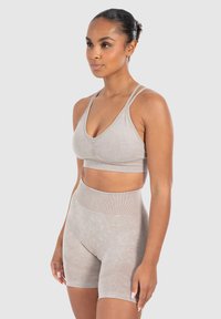 Conjunto de sujetador deportivo beige y pantalones cortos de tiro alto, con un tejido suave y texturizado, correas ajustables y un diseño sin costuras.