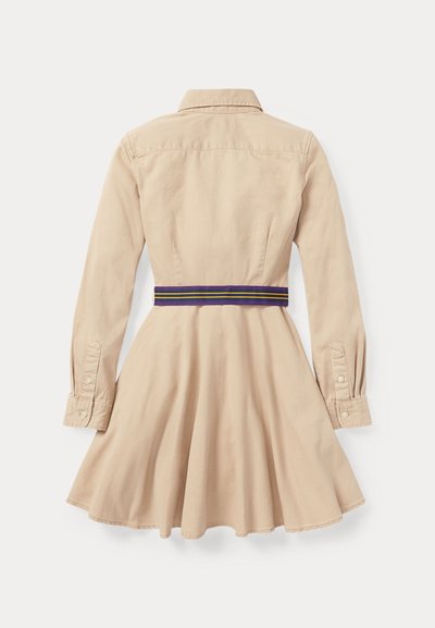 Bežīga kokvilnas kleita ar pieguļošu augšdaļu, pilnu svārku, garām piedurknēm un violeti svītrotu vidukļa jostu. Ar pogām auklā un apkakles detaļām.