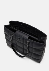 Black quilted tote bag with chain and leather handles, featuring an interior zipper pocket and a branded emblem on the exterior.