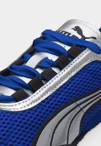 Μπλε αθλητικό παπούτσι Puma από δίχτυ με ασημί και μαύρες λεπτομέρειες, μπλε κορδόνια και το λογότυπο Puma στη γλώσσα.