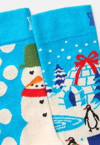 Meias de malha com um fundo azul, bonecos de neve, pinguins e um design de iglu em cores vibrantes. Textura suave com punhos canelados confortáveis.
