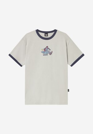 Béžové tričko s námornícky modrým golierom a lemami rukávov, zdobené malou farebnou grafikou osoby oddychujúcej pri budovách a palmách.