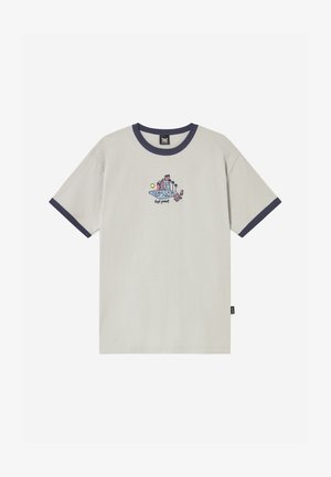 Béžové tričko s námornícky modrým golierom a lemami rukávov, zdobené malou farebnou grafikou osoby oddychujúcej pri budovách a palmách.