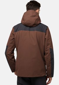 Giacca impermeabile marrone con una sezione superiore nera, cappuccio e design aderente. Presenta una texture liscia e tasche laterali con zip.