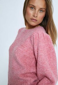 Rosa, strukturiertes Sweatshirt mit rundem Ausschnitt und puffigen Ärmeln. Weicher Stoff mit einer dezenten, flauschigen Oberfläche, die einen lockeren Sitz bietet.