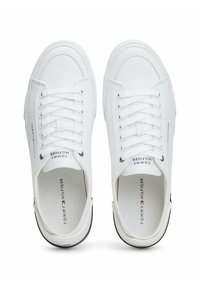 Zapatillas de lona blancas con un diseño de corte bajo, puntera redonda, parte delantera con cordones, detalle del logo y franja negra en la suela. Plantilla texturizada.