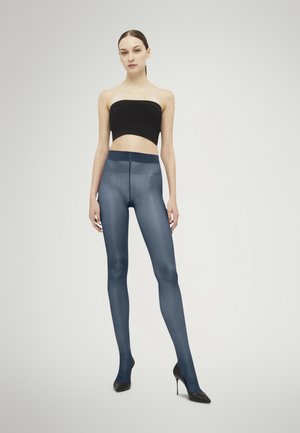 Mörkblå genomskinliga leggings med en slät textur, hög midja och bred midjeband, kombinerat med en svart strapless topp och klackar.