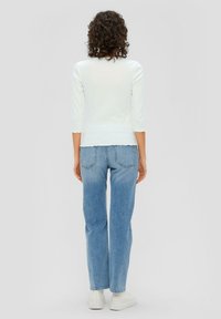 Lichtblauw geribbeld topje met driekwartmouwen, gegolfde zoom, gecombineerd met hooggeribde lichtblauwe jeans en chunky witte sneakers.