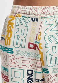 Cotton sweatpants with an elastic waistband. Features vibrant, multi-colored printed letter designs on a light background.