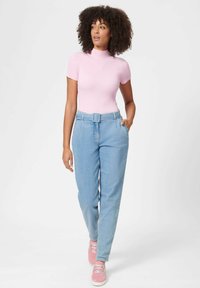 Hellrosa kurzärmeliges, geripptes Oberteil kombiniert mit hoch taillierten, hellblauen Jeans mit geradem Bein und rosa Sneakern. Einfaches Design, lässige Passform.