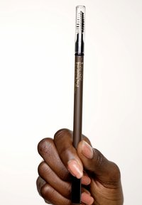 Crayon à sourcils en brun foncé avec une pointe effilée et un capuchon transparent. Comprend une brosse spoolie à l'autre extrémité pour le mélange.