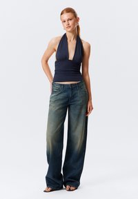 Top a fascia blu navy con un corpetto aderente, abbinato a jeans in denim a gamba larga con una leggera sfumatura e design classico a cinque tasche.