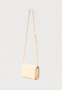 Mala bež kožna torbica preko tijela s dugim podesivim remenom i više pretinaca, prikazana na jednostavnoj pozadini.