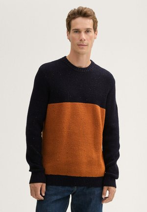 Gebreid sweater met een marineblauwe bovenkant en een oranje onderkant, met een geribbelde textuur en een ronde halslijn.