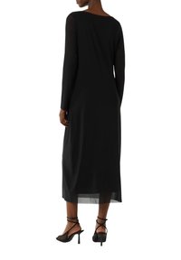 Robe noire à manches longues avec une coupe décontractée, en tissu léger, dotée d'un col rond et d'une longueur mi-mollet. Élégantes sandales à talons.