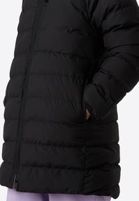 Veste rembourrée noire avec texture matelassée, fermeture éclair intégrale et poches latérales. Matière douce et isolante conçue pour la chaleur et le confort.