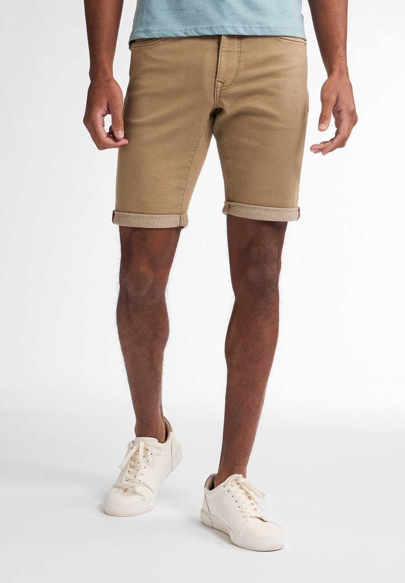 Khaki denim shorts with rolled cuffs, five-pocket design, and a slim fit, complemented by white textured sneakers.