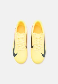Żółte buty sportowe z teksturowaną powierzchnią, czarnymi akcentami i wzorem w zygzak. Posiadają sznurowany design i wyściełane wnętrze.