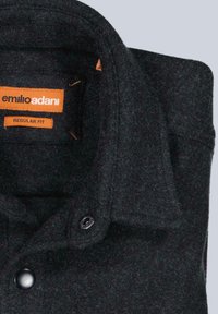 Schwarzes gefaltetes Wollhemd mit knöpfbarem Kragen, ausgestattet mit orangefarbenen Etiketten mit der Aufschrift "emilio adani" und "regular fit" im Nackenbereich.