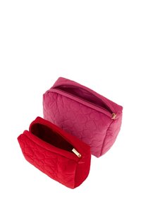 Twee ritszakken, één roze en één rood, met een hartjespatroon en een quilttextuur. De roze zak is groter, beide hebben gouden ritsbeslag.