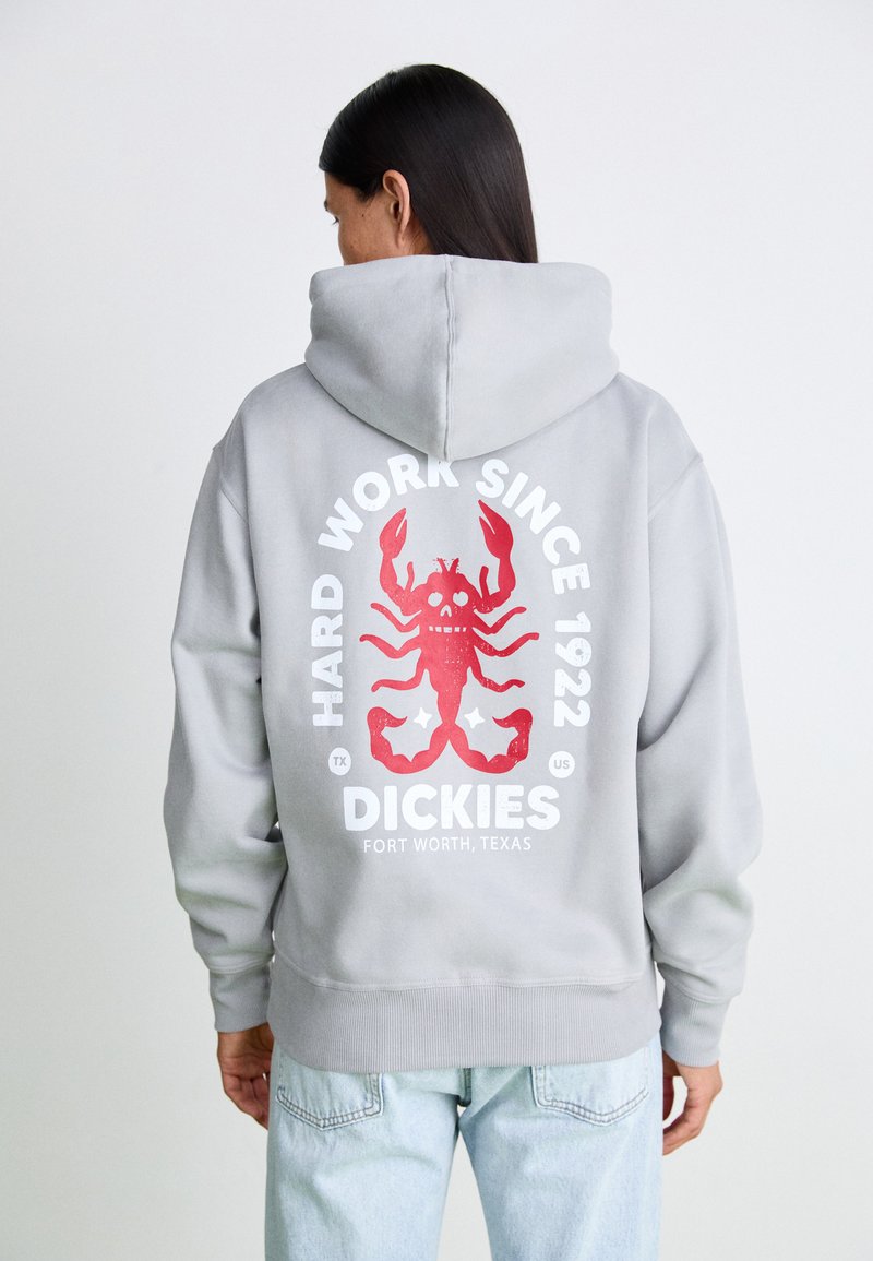 Grå huvtröja med en stor röd krabbgrafik på baksidan, med texten "HARD WORK SINCE 1922" och "DICKIES" i vitt.