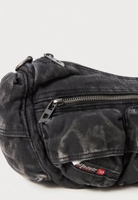 Schwarze Jeansstofftasche mit Reißverschluss und strukturierten Oberflächen, ausgestattet mit einer Fronttasche, metallischen Beschlägen und dezenten Verblassungsmustern.