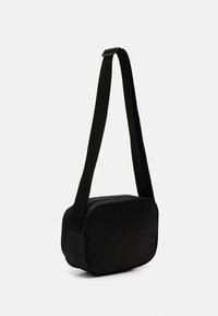 Černá crossbody taška obdélníkového tvaru, vyrobená z hladkého textilního materiálu. Obsahuje pevný popruh a zipové uzavření.