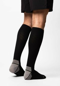 Black knee-high socks with textured fabric, featuring a gray heel and toe design with horizontal stripes and ribbed top.