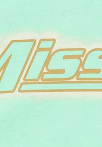 La tela verde menta presenta letras doradas en negrita con la palabra "Miss", transmitiendo una textura suave y un vibrante contraste de color.