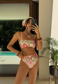 Spalvinga dviejų dalių bikinio komplektas su raštuotu dizainu rožinės, oranžinės ir mėlynos spalvų atspalviais. Medžiaga atrodo lygi, aptempto silueto.