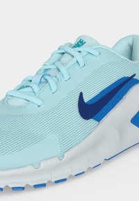 Ανοιχτού μπλε παπούτσι τρεξίματος Nike με σκούρο μπλε λογότυπο swoosh, λευκή σόλα και ασορτί ανοιχτό μπλε κορδόνια σε μονόχρωμο φόντο.