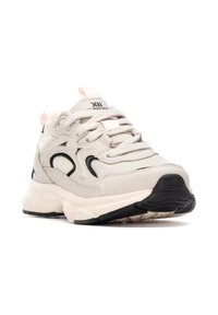 Zapatillas beige con acentos en negro, parte superior de malla texturizada, cuello acolchado y suela ligera. Presenta cordones redondos y una pestaña en el talón.