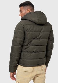 Dunkelgrüne Steppjacke mit horizontalen Steppmustern, Kapuze und strukturiertem Stoff. Gestreift und isoliert für Wärme.